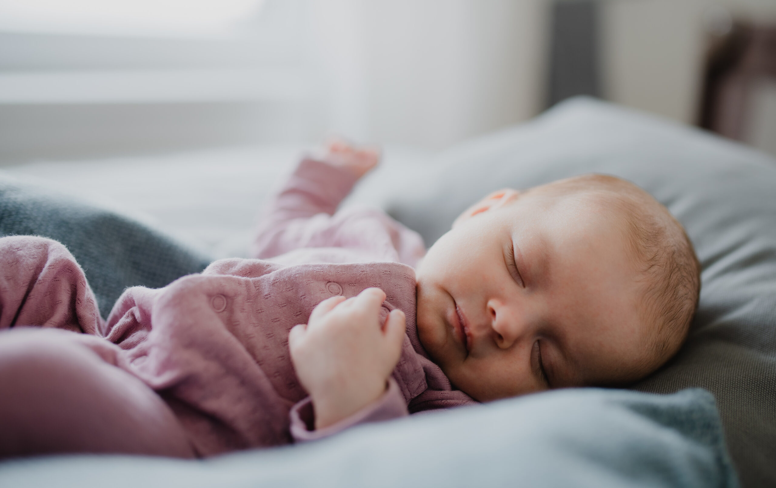 Portrait of cute newborn baby girl, sleeping an lying on sofa indoors at home.