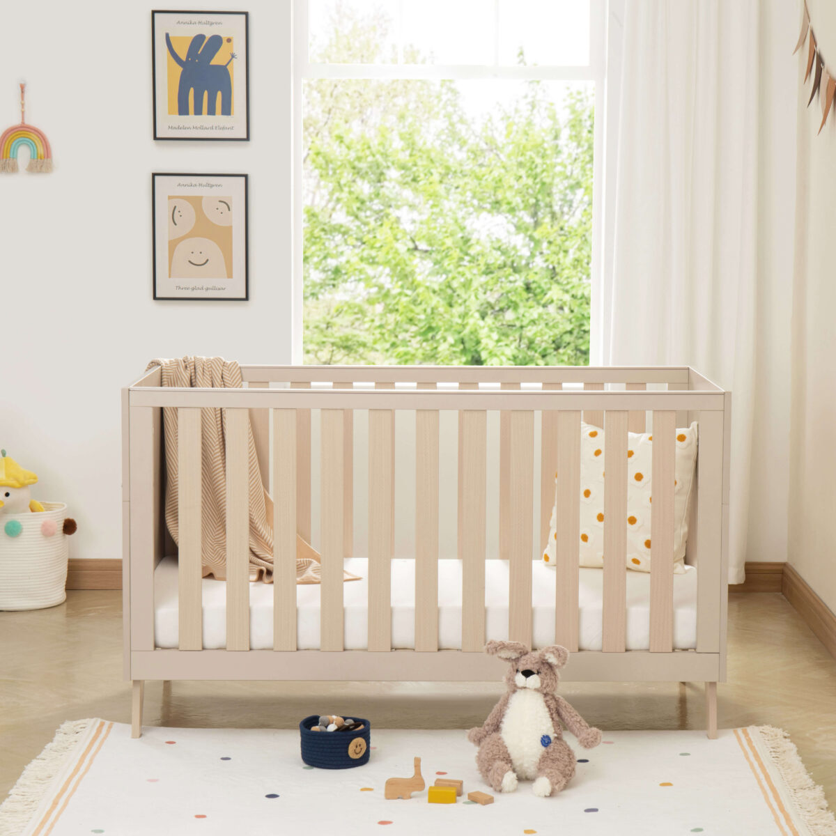 Front view of Babymore Dante Cot Bed in cashmere wood finish, styled in a bright nursery.