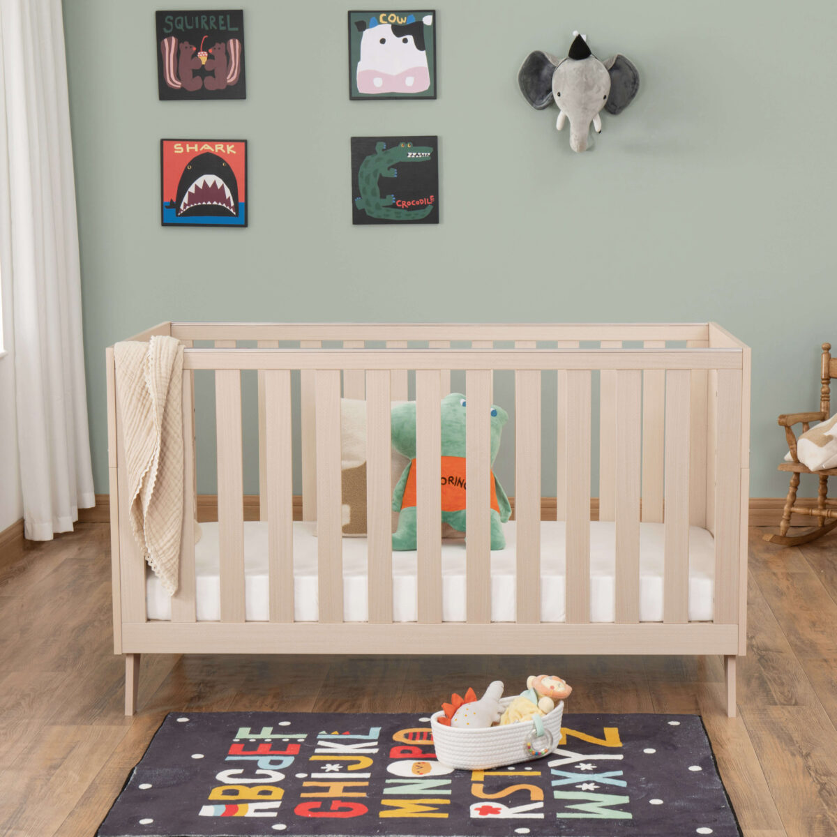 Front view of Babymore Dante Cot Bed in natural wood with playful decor and alphabet rug.