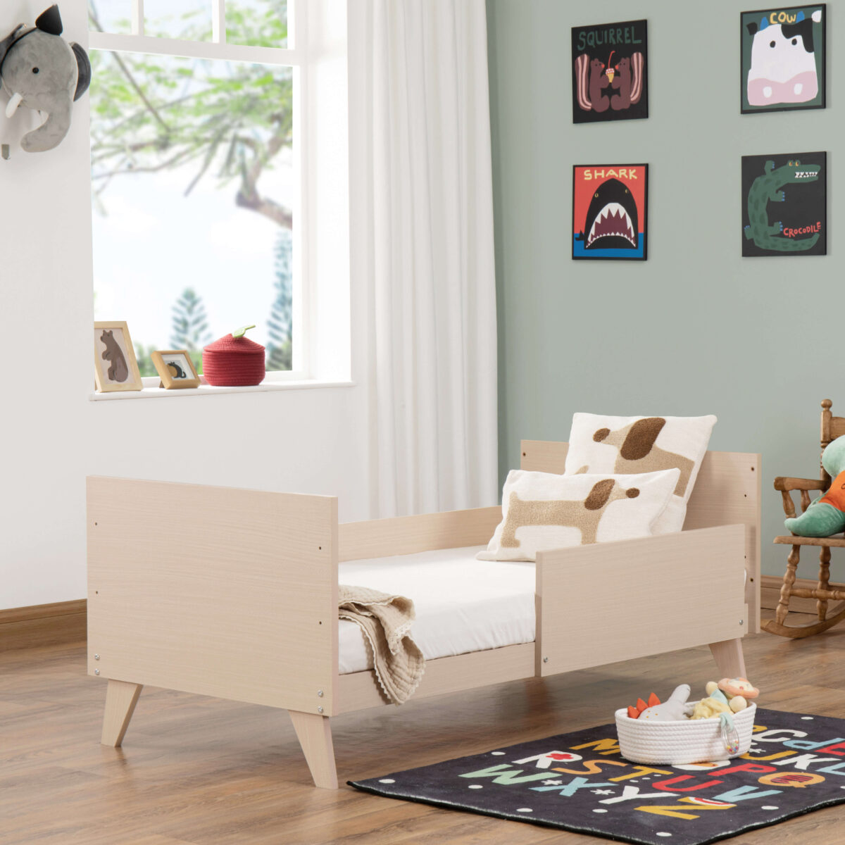 Babymore Dante Cot Bed shown as a toddler bed with side guard and soft dog-themed pillows.