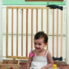 Clippasafe Extendable Dual Fix Wooden Baby Stair Gate with baby or Child sat in front of the barrier.