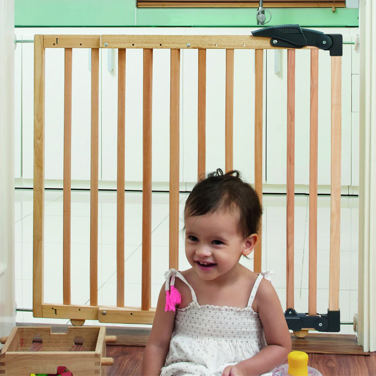 Clippasafe Extendable Dual Fix Wooden Baby Stair Gate with baby or Child sat in front of the barrier.