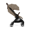 A side view of the beige stroller, showcasing its extended canopy, adjustable reclining seat, and sturdy black frame. The stroller appears lightweight and designed for easy maneuverability.