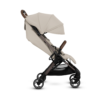A side view of the beige stroller, showing its extended canopy, reclined seating position, and brown leather-look handlebar. The black frame and four swivel wheels highlight its lightweight and portable design.