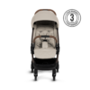 A front-facing view of the stroller with its beige fabric, brown handlebar, and five-point harness system. A 
