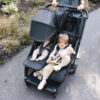 Uppababy-Minu-Duo-Twin-Pushchair-Jake-Black-Lifestyle-001-Seat-Reclined-Extended-Hood-and-Upright