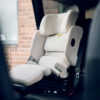AXKID Up High Back Booster Car Seat in white installed in a car, viewed from the passenger side.
