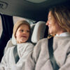 Child and parent smile at each other while seated in AXKID Up High Back Booster Car Seat inside a car.