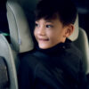Close-up of a smiling boy comfortably seated in the AXKID Up High Back Booster Car Seat.