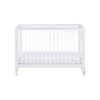 Front-facing white cot bed with clear slats and gold legs, shown on plain white background.