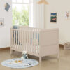 Cashmere cot bed in bright nursery with soft blue accents and playful decor.