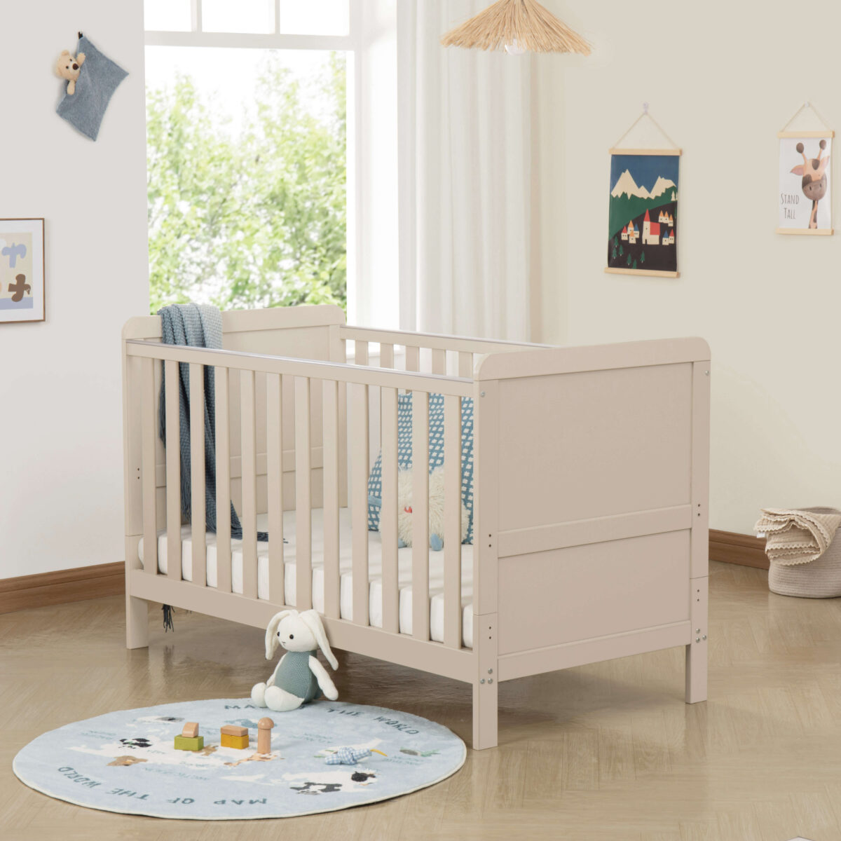 Cashmere cot bed in bright nursery with soft blue accents and playful decor.