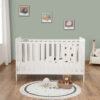 Front view of white cot bed with wall art, toys and soft panda-themed bedding.