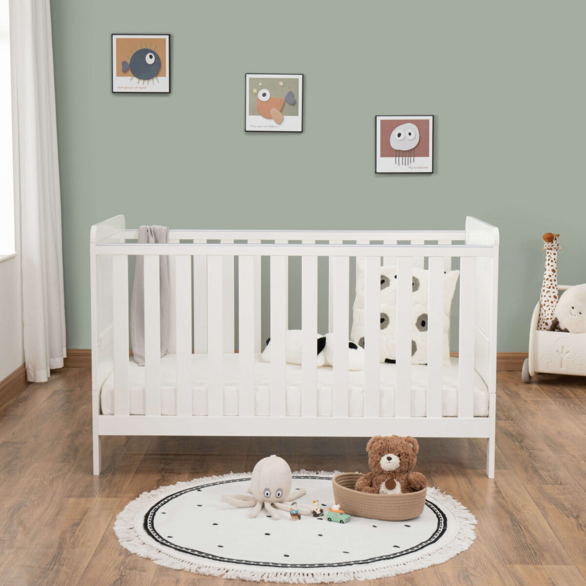 Front view of white cot bed with wall art, toys and soft panda-themed bedding.