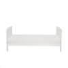 Side view of toddler bed in white with simple design and soft curved edges.