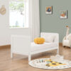 White toddler bed setup with pumpkin pillow, toys and soft natural light.