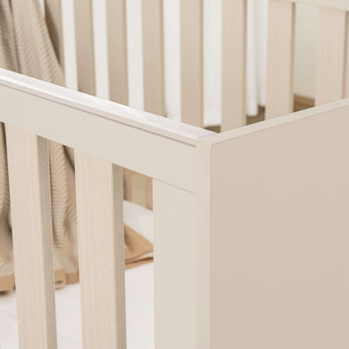 Close-up of Babymore Dante Mini Cot Bed in cashmere highlighting slats and smooth finish.