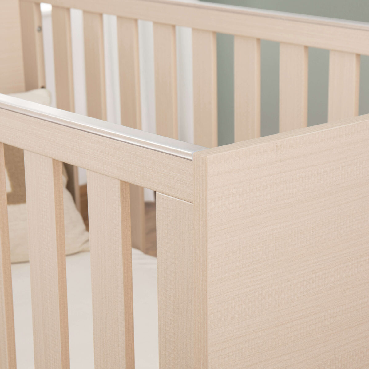 Close-up of Babymore Dante Mini Cot Bed showing smooth natural wood texture and rails.