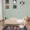 Side view of Babymore Dante Mini Cot Bed in toddler mode with comfy bedding and rug.