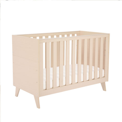 Studio view of Babymore Dante Mini Cot Bed in cot mode with natural wood slats.