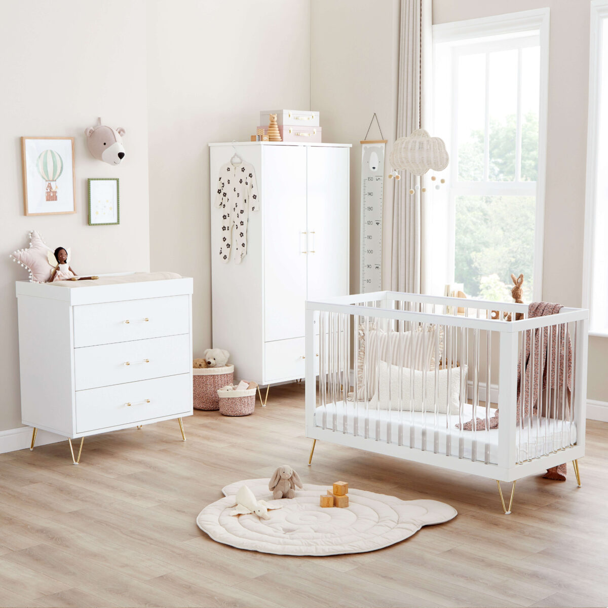 Bright nursery with white furniture set, soft rug, and large windows letting in natural light.