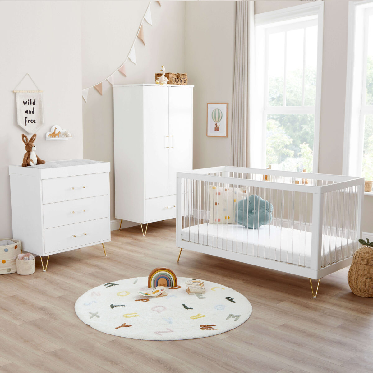 Bright nursery with white crib, dresser, wardrobe, and a round alphabet rug.
