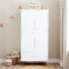 White wardrobe with gold legs, soft toy baskets, and decorative bunting in a corner.