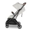 Side view of white UPPAbaby stroller with dark brown leather handlebar and bumper bar.
