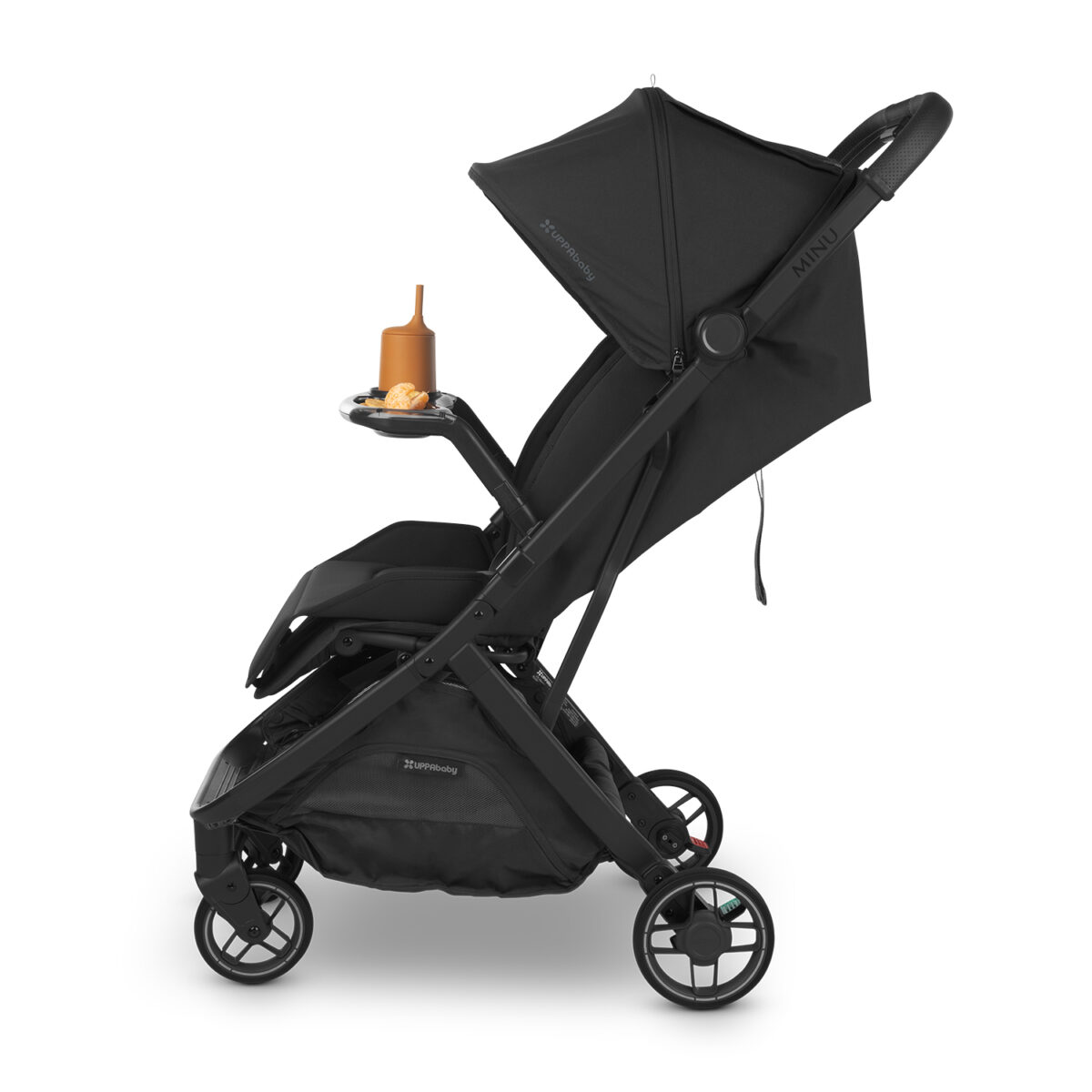 Side view of stroller with snack tray holding a brown sippy cup and snacks on the tray surface.