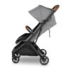 Side view of grey UPPAbaby stroller with brown leather handlebar and bumper bar.